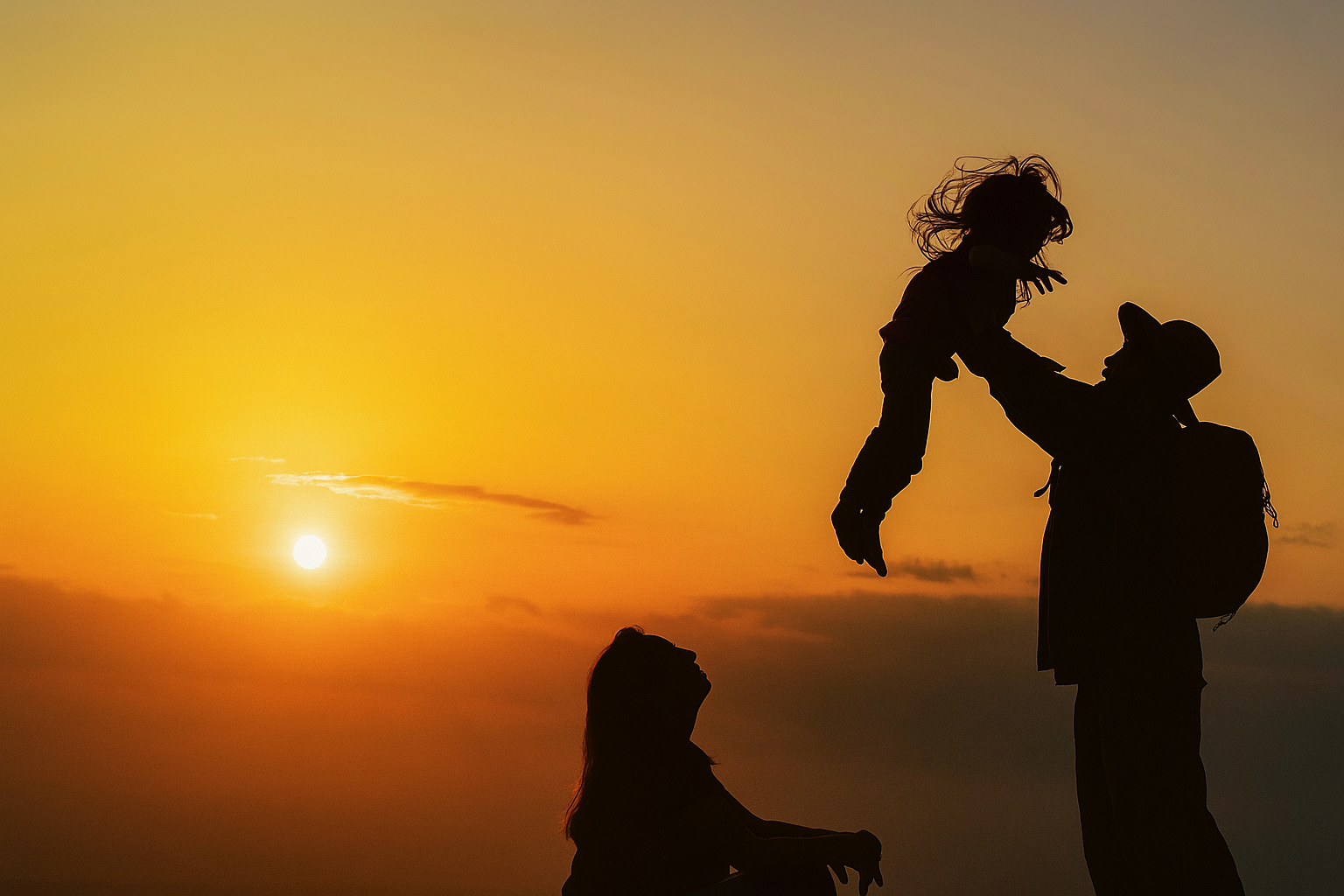Silhouette d'une famille au coucher du soleil - parent soulevant un enfant dans ses bras